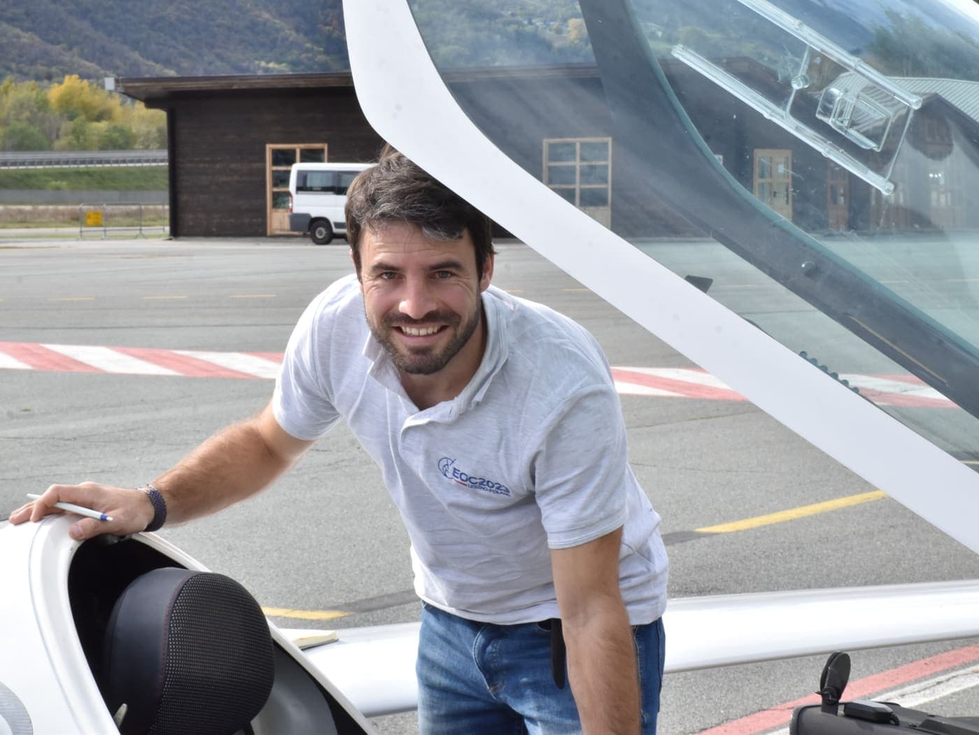 Swiss Sailplane founder beside a glider canopy at an Alpine airfield