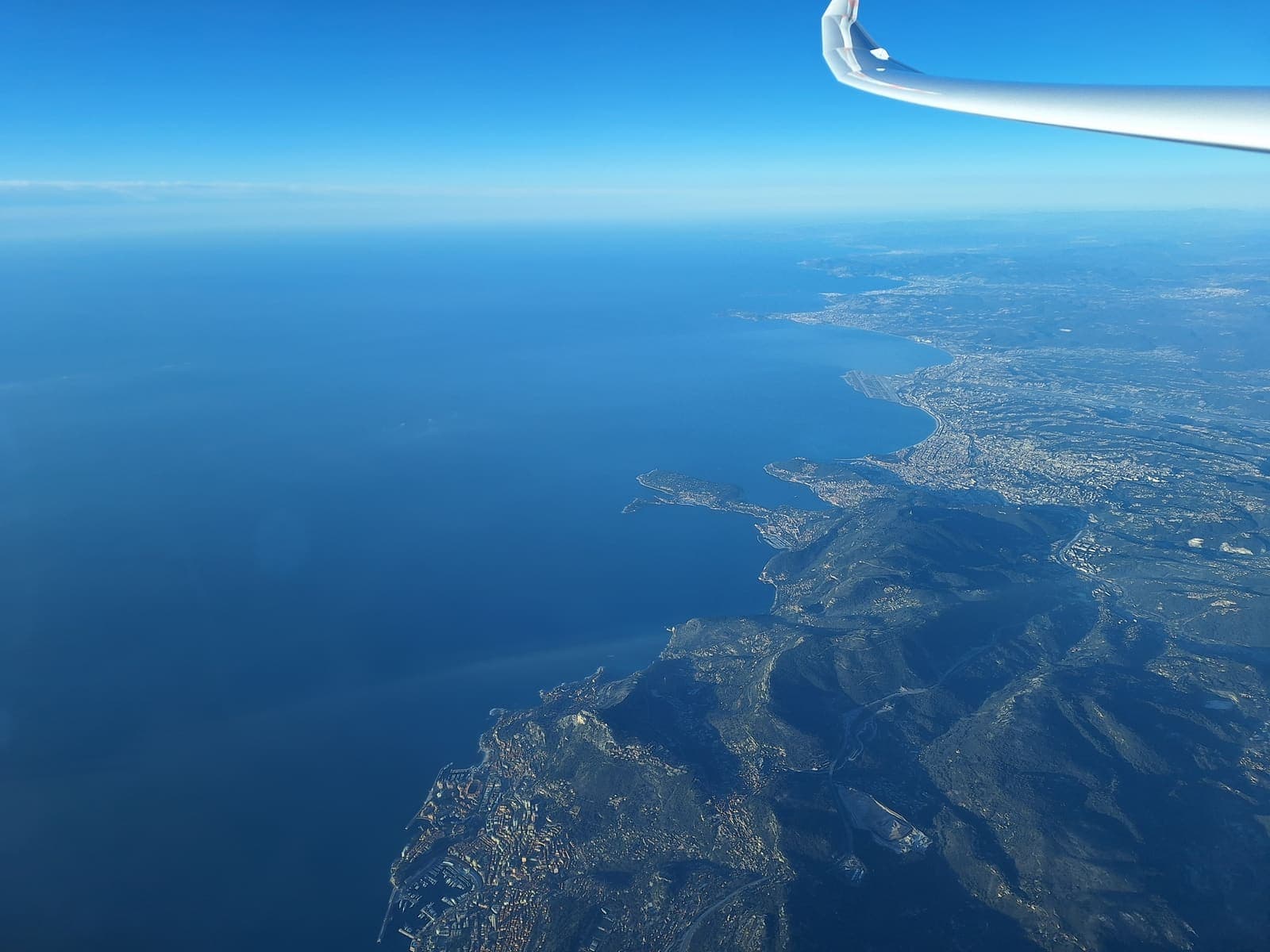 Die Küste der Côte d'Azur tief unter der Tragfläche beim Verlassen des Festlands